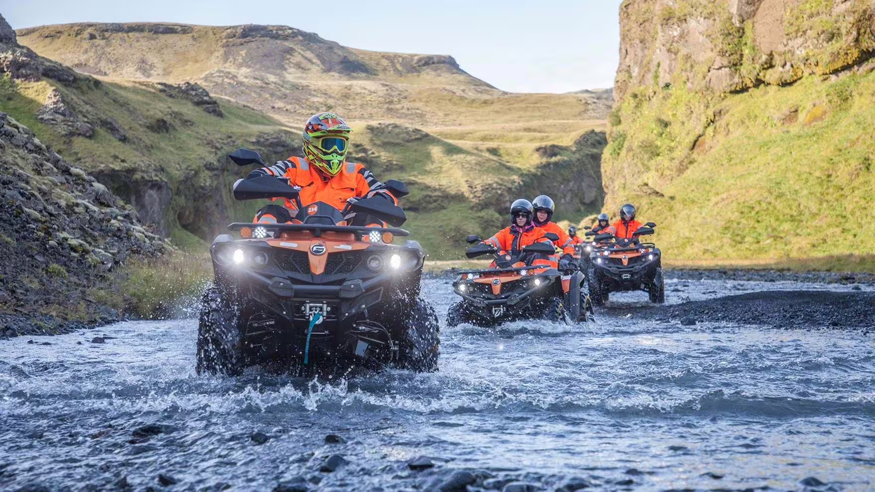ATV riders splash through a river canyon on a private Iceland South Coast adventure from Reykjavík