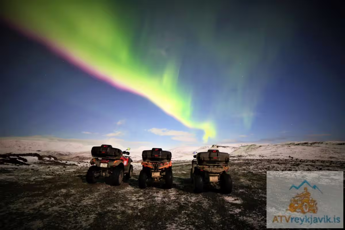 Three ATVs parked under vibrant green and pink northern lights over snowy Icelandic landscape at night