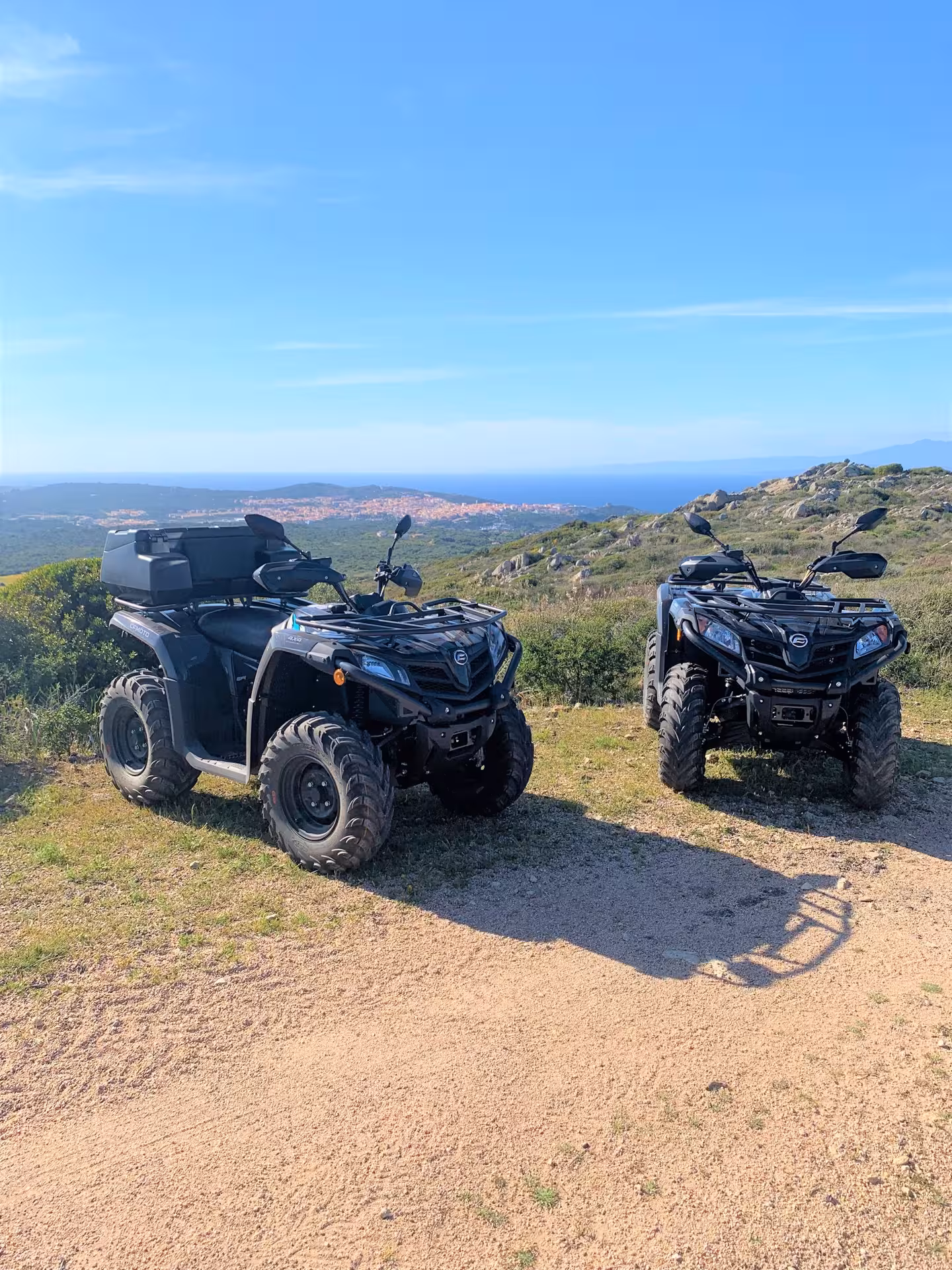 Pair of ATVs on a scenic hillside with panoramic views of Santa Teresa di Gallura's coastline.