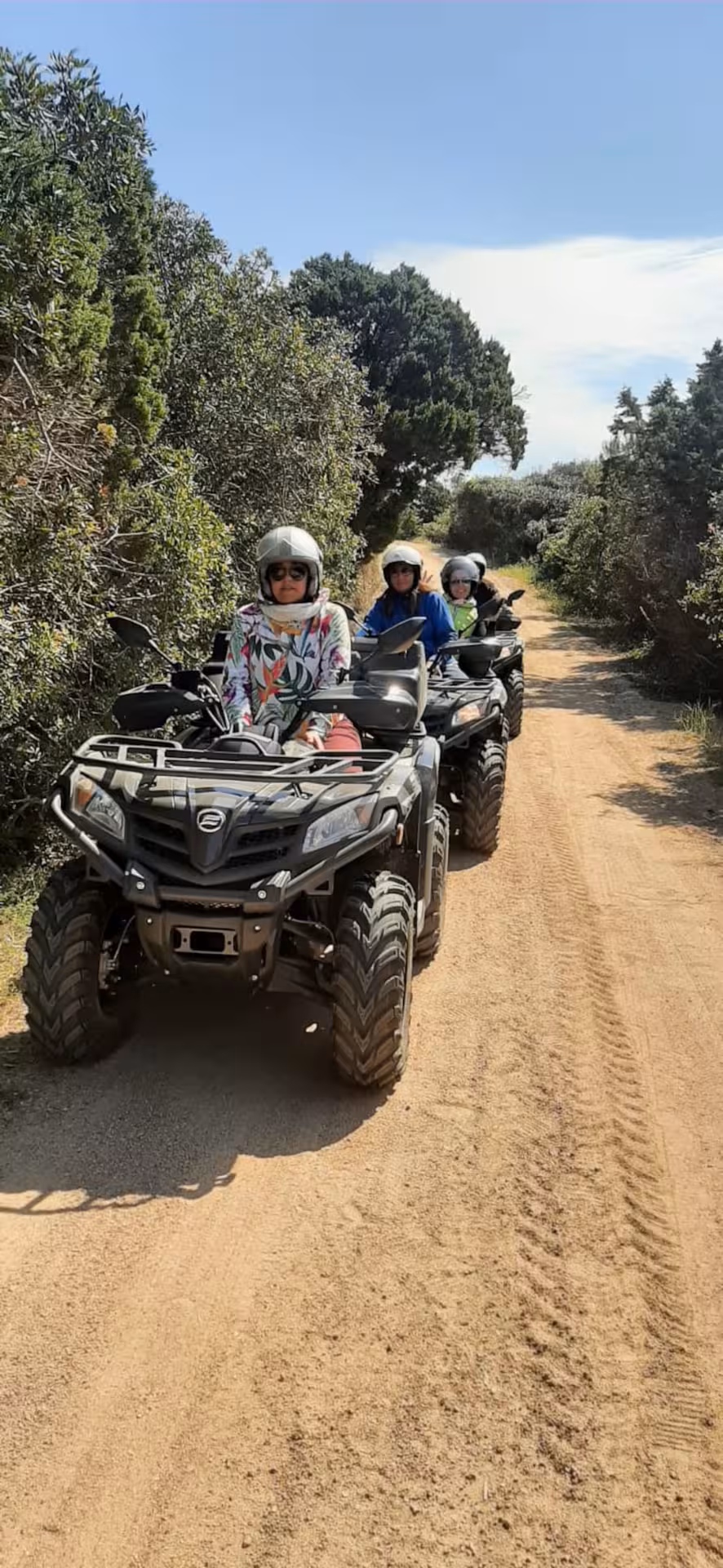 Group of ATV riders exploring a sandy trail surrounded by lush greenery in Santa Teresa di Gallura.