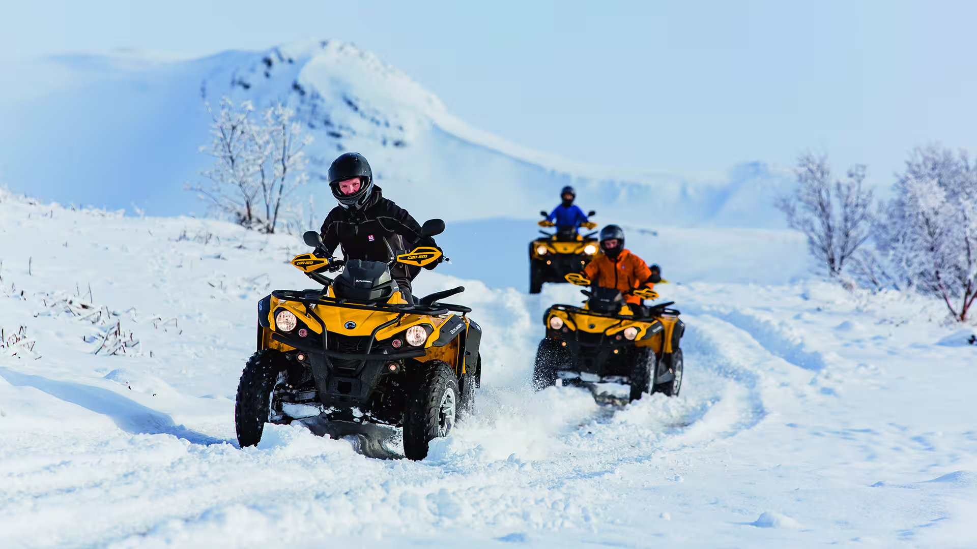 Adventurers ride ATVs through a snowy landscape, highlighting an exhilarating winter caving and off-road experience.