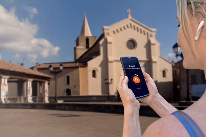 Tourist using GPS audio guide app on smartphone in front of Église Saint-Sauveur in Aubagne, France