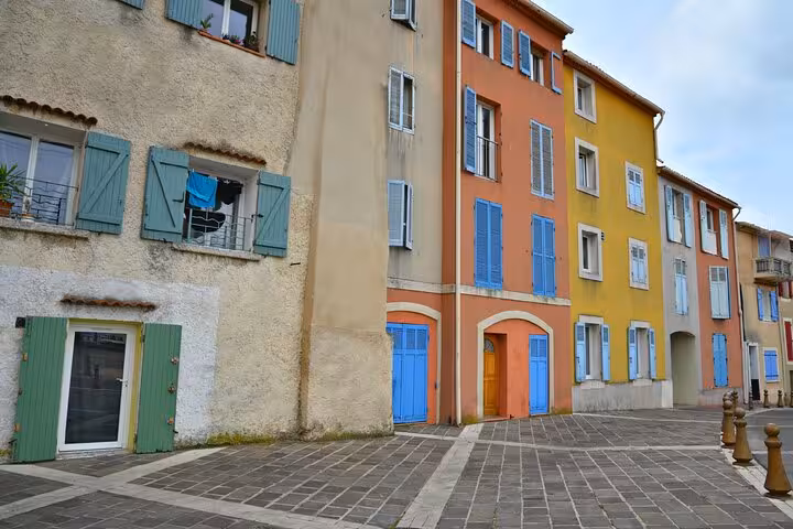 Colorful Provençal building facades with blue shutters on a cobblestone square in Aubagne, France