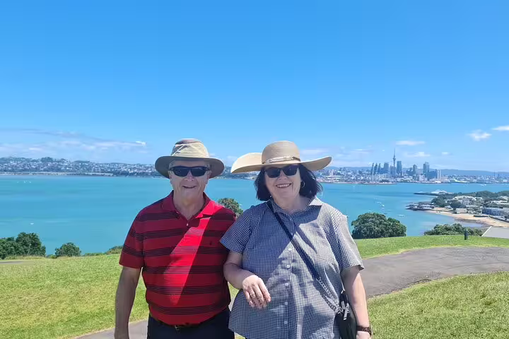 Couple enjoying a sunny day with Auckland's skyline and harbor as a scenic backdrop during city highlights tour.