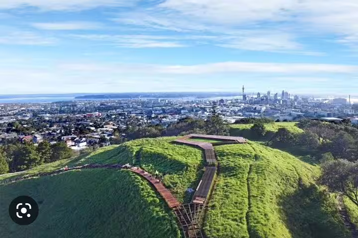 Panoramic view of Auckland city skyline from a lush green hilltop, perfect for a private day tour.