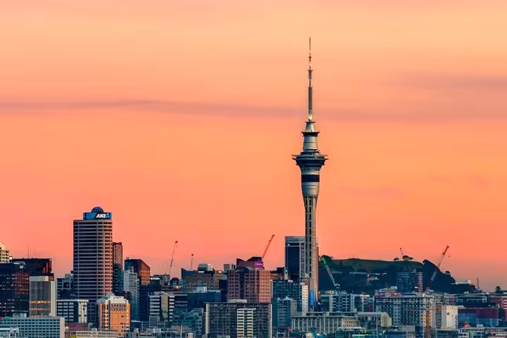 Auckland skyline at sunset featuring the iconic Sky Tower rising above city buildings