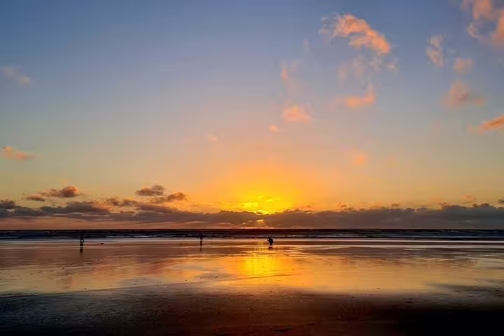 Serene Auckland sunset over ocean reflecting vibrant colors on beach for romantic tour with winery and spa.