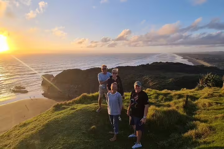 Tourists basking in the golden hues of an Auckland sunset, highlighting the allure of winery and thermal pool tours.