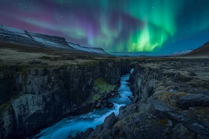 Northern lights dancing over a rocky canyon with turquoise river in Iceland's golden circle region