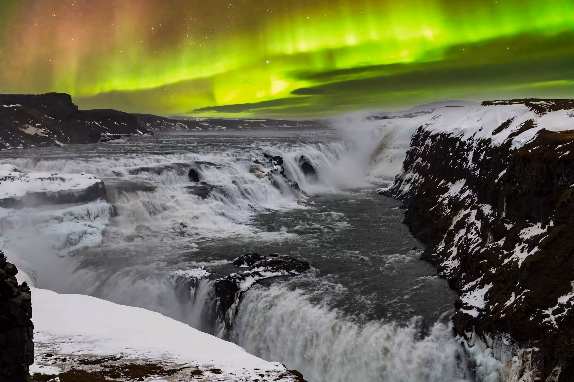 Aurora Borealis illuminating Gullfoss waterfall with vibrant colors during Iceland stopover tour, highlighting natural wonder.