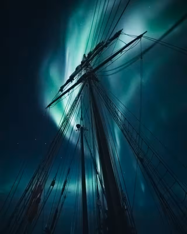 Breathtaking aurora borealis illuminating ship mast on exclusive Arctic Northern Lights luxury cruise night voyage