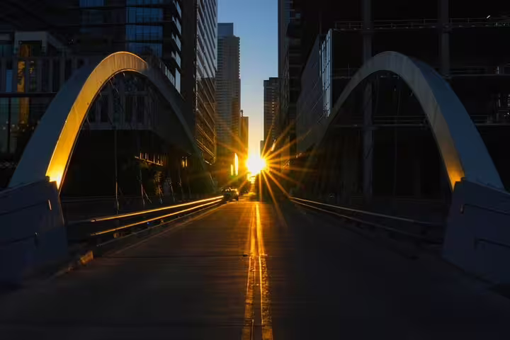 Dramatic sunrise over an urban bridge with glowing arches and city skyscrapers in Austin, Texas