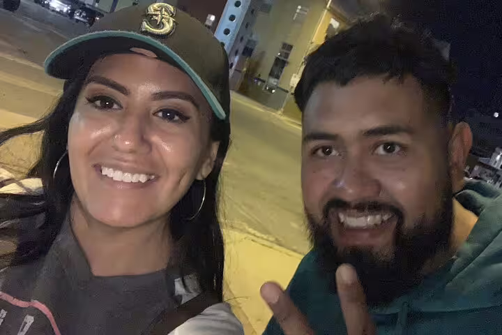 Two smiling people posing for a selfie at night on a city street in Austin