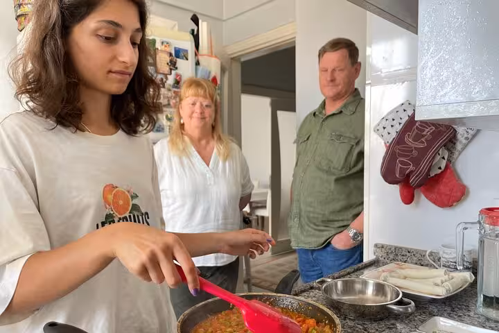 Guest stirs menemen in a home kitchen during authentic homemade Turkish breakfast cooking with local friends