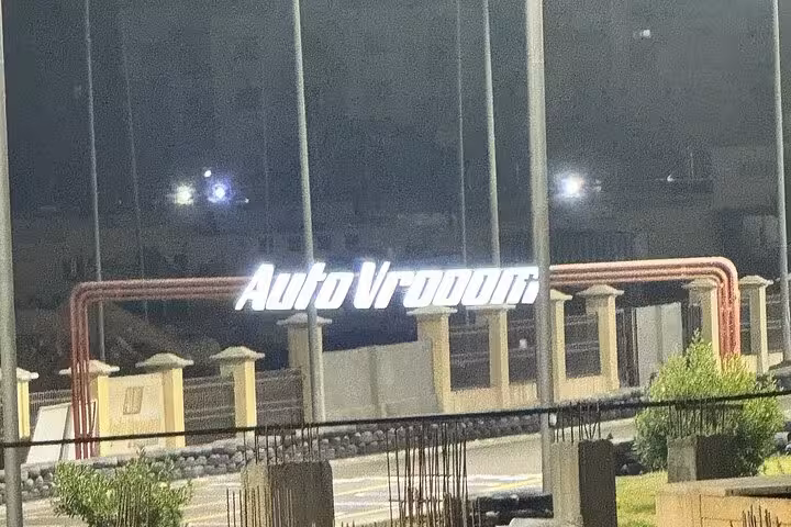 Illuminated AutoVrooom entrance sign at night, marking the AUTOVROOOM go-karting experience venue