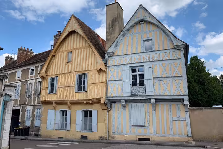 Historic half-timbered medieval houses with yellow and blue facades on a street in Auxerre, France