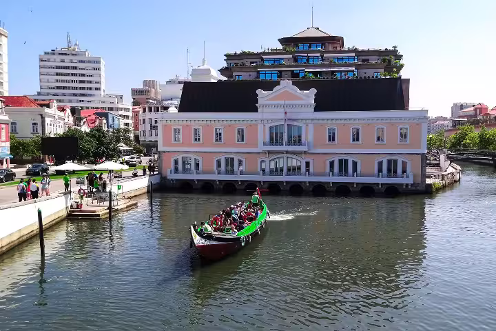 Scenic view of a colorful boat tour on the canal in Aveiro, with charming architecture and vibrant atmosphere in the background.