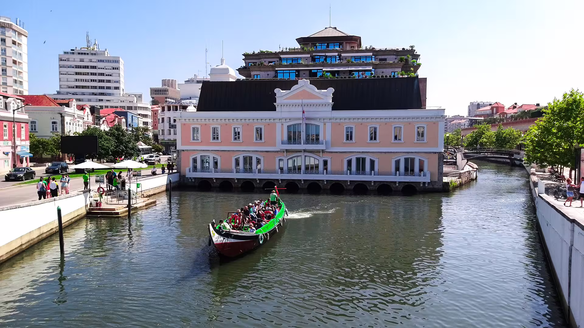 Colorful boat navigates Aveiro canal past historic architecture on a private tour featuring sparkling wine cellars and piglet tasting.