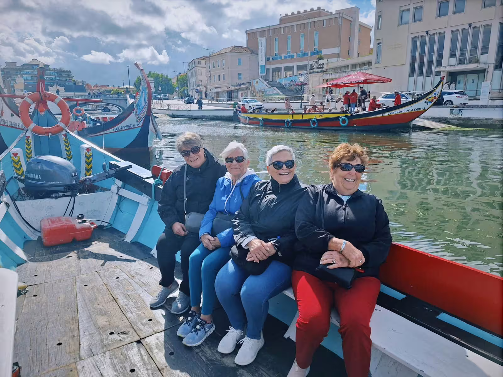 Visitors enjoying a moliceiro boat ride on Aveiro's canals, experiencing the vibrant cityscape and waterways.