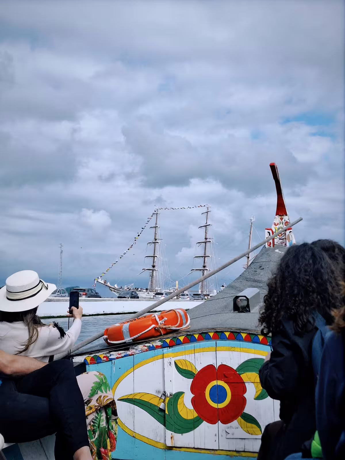 Tourists enjoy a colorful moliceiro boat ride in Aveiro's picturesque canal during a vibrant city tour.
