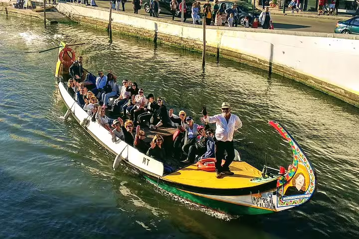 Tourists enjoy a scenic ride on a traditional moliceiro boat in Aveiro, Portugal, part of the Porto day trip experience.