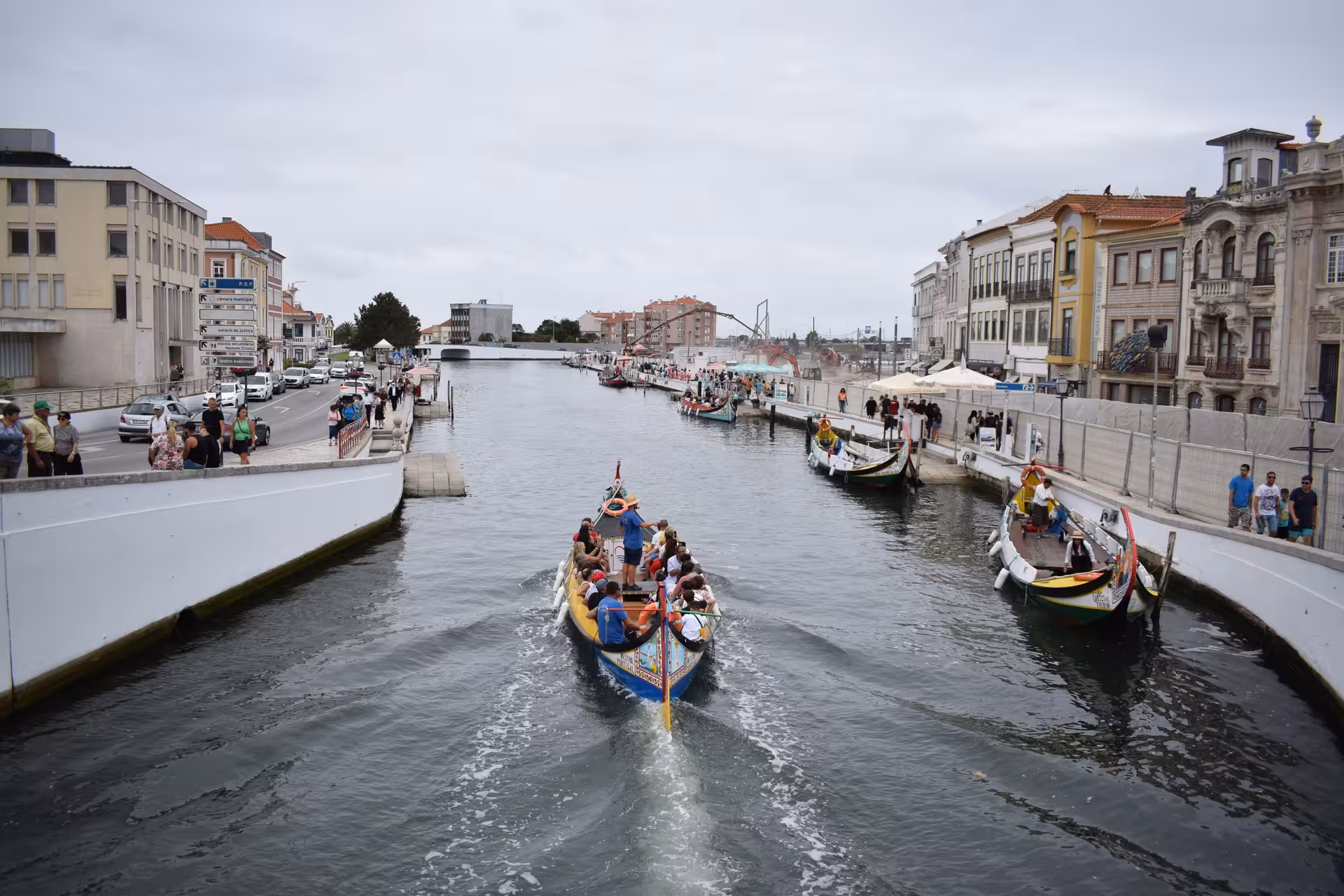 Colorful Moliceiro boat ride through Aveiro canal on a private half-day tour, passing historic waterfront