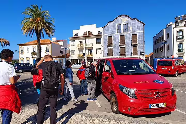 Tourists gather near a red tour van in Aveiro's scenic town square, preparing for the Moliceiro river cruise adventure.