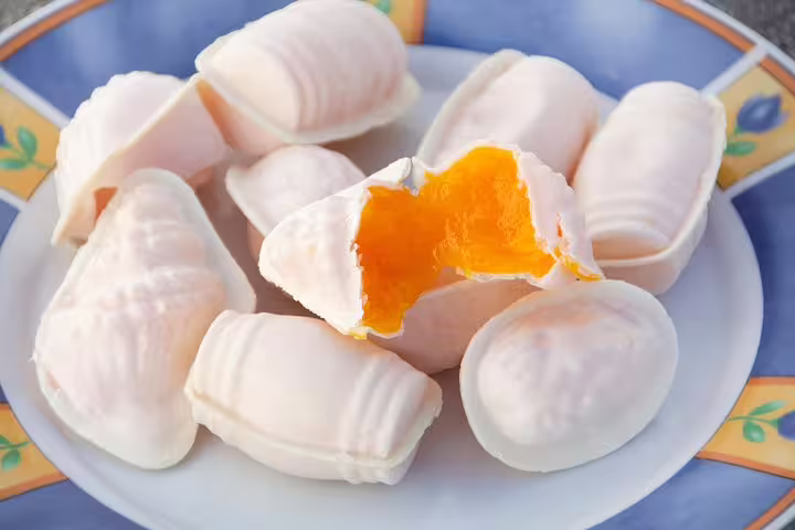 Plate of traditional Portuguese ovos moles with a vibrant orange filling, a sweet delicacy from Aveiro, Portugal.