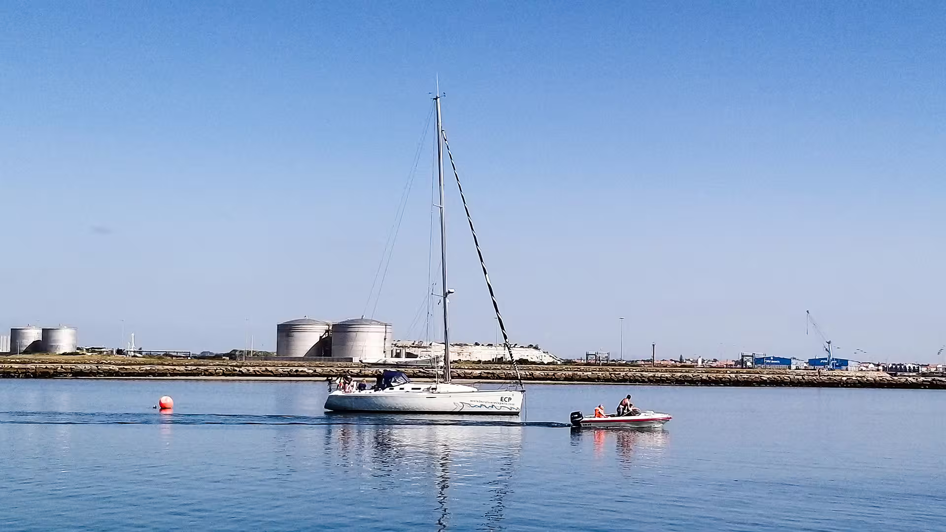 Sailboat glides through calm waters in Aveiro, offering scenic views of the port, perfect for a private tour with wine tasting.