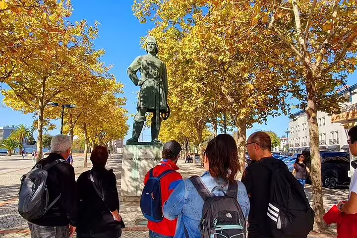 Tourists admire a statue surrounded by golden autumn trees during the Aveiro half-day tour from Porto.