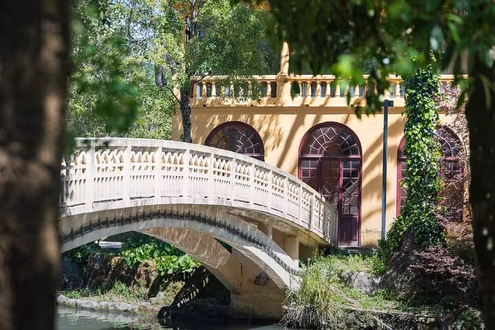 Ornate white stone bridge over a canal with a yellow historic building in Aveiro, Portugal