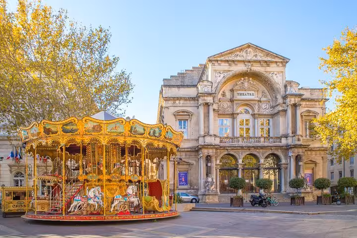 Ornate golden carousel in front of the historic Theatre Municipal in Avignon, France