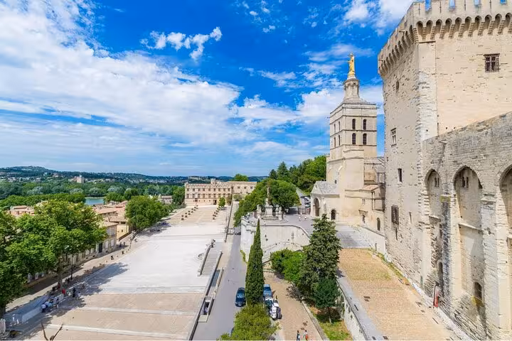 Aerial view of Avignon Papal Palace and cathedral with vast courtyard and Rhône River in background