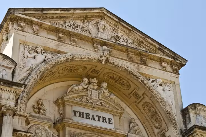 Intricate stone carvings adorn the historic facade of Avignon's grand theater, a highlight on the private city walk tour.