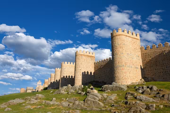 Majestic medieval walls of Avila under a clear blue sky, showcasing historic architecture on guided tour.
