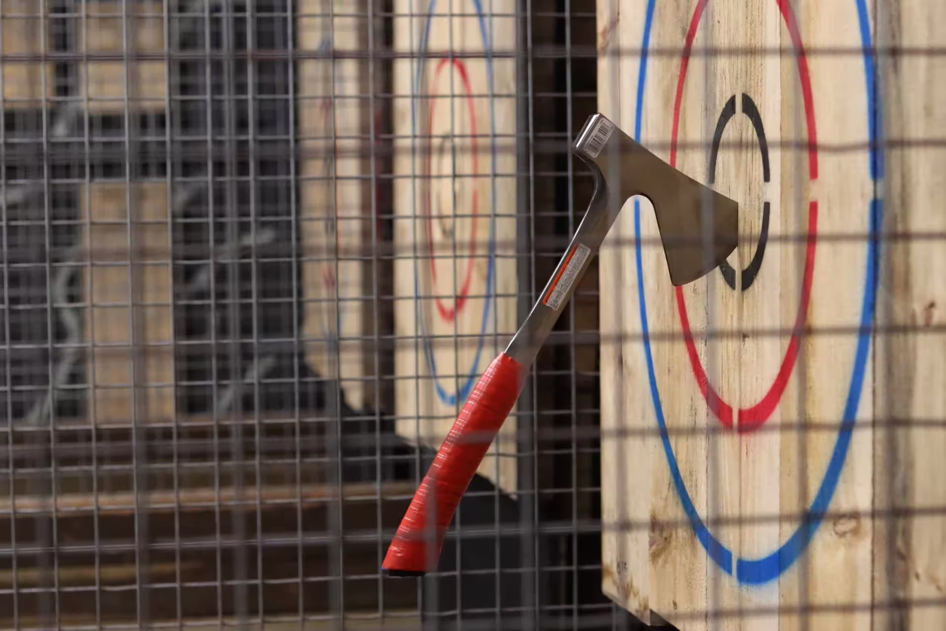 Axe stuck in wooden bullseye target at Amsterdam axe throwing venue, fun indoor activity with safety cage