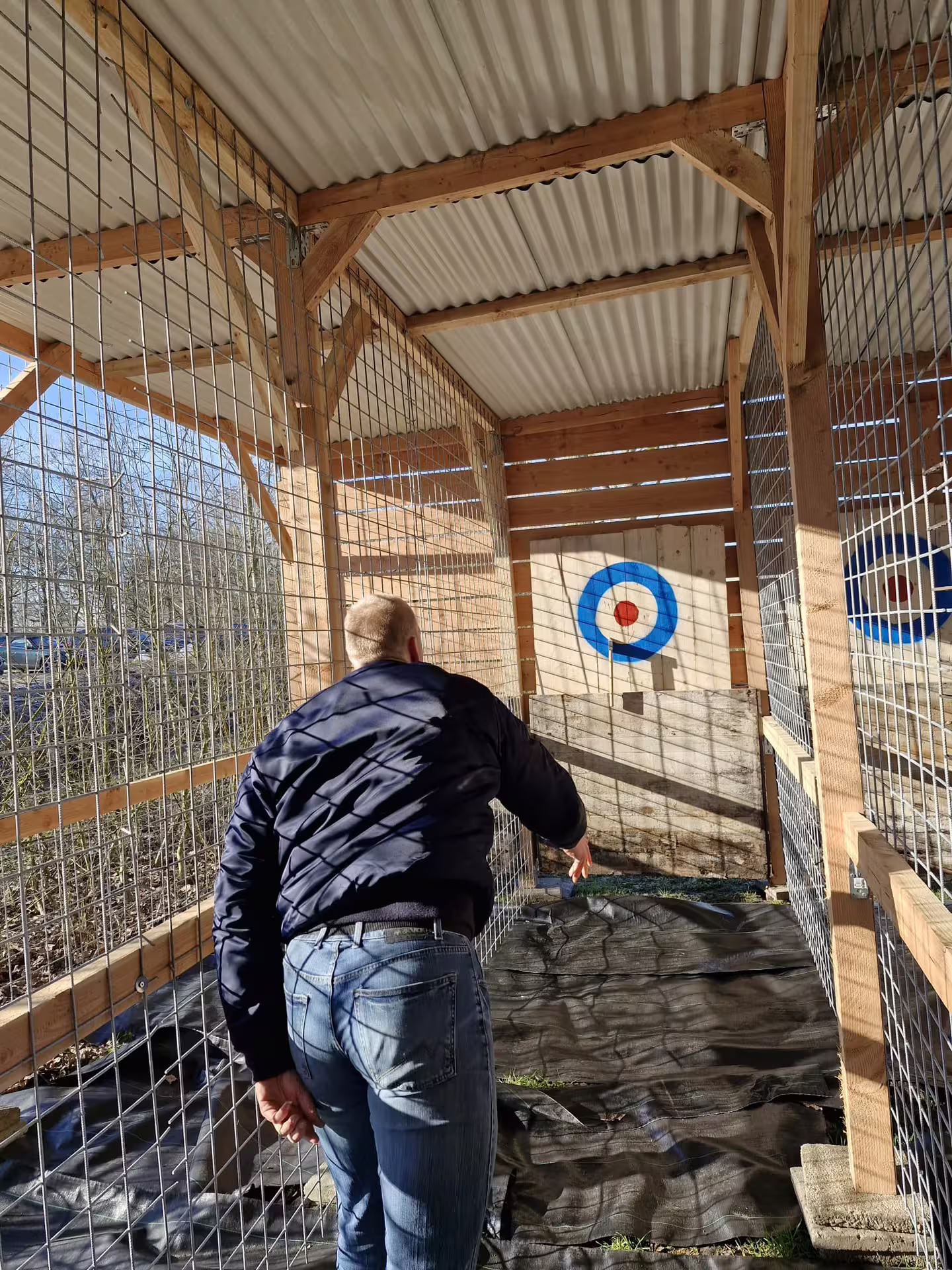 Participant throwing an axe at a bullseye target in Amsterdam, private lane with safety cage, urban adventure tour
