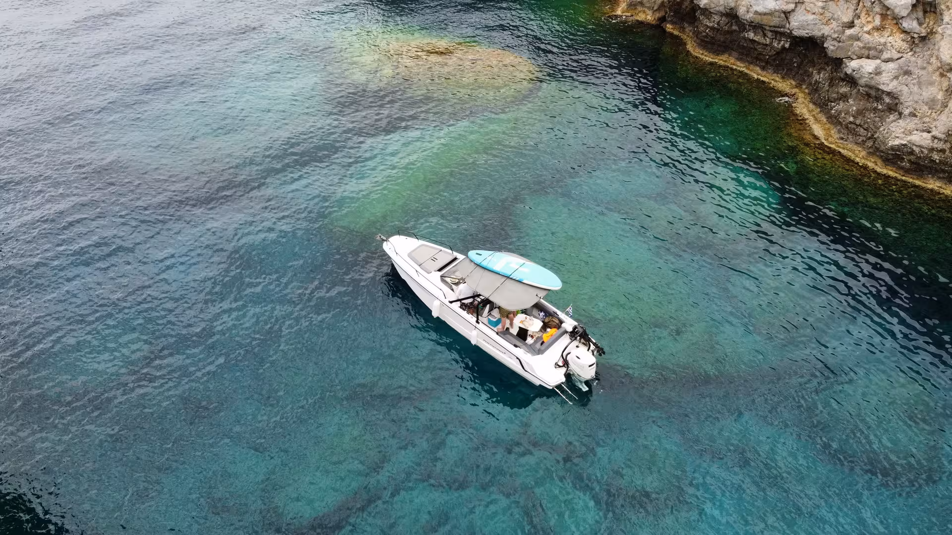 Aerial view of Axopar 25 CT boat anchored in crystal-clear Blue Lagoon waters near rocky coast, Rhodes cruise