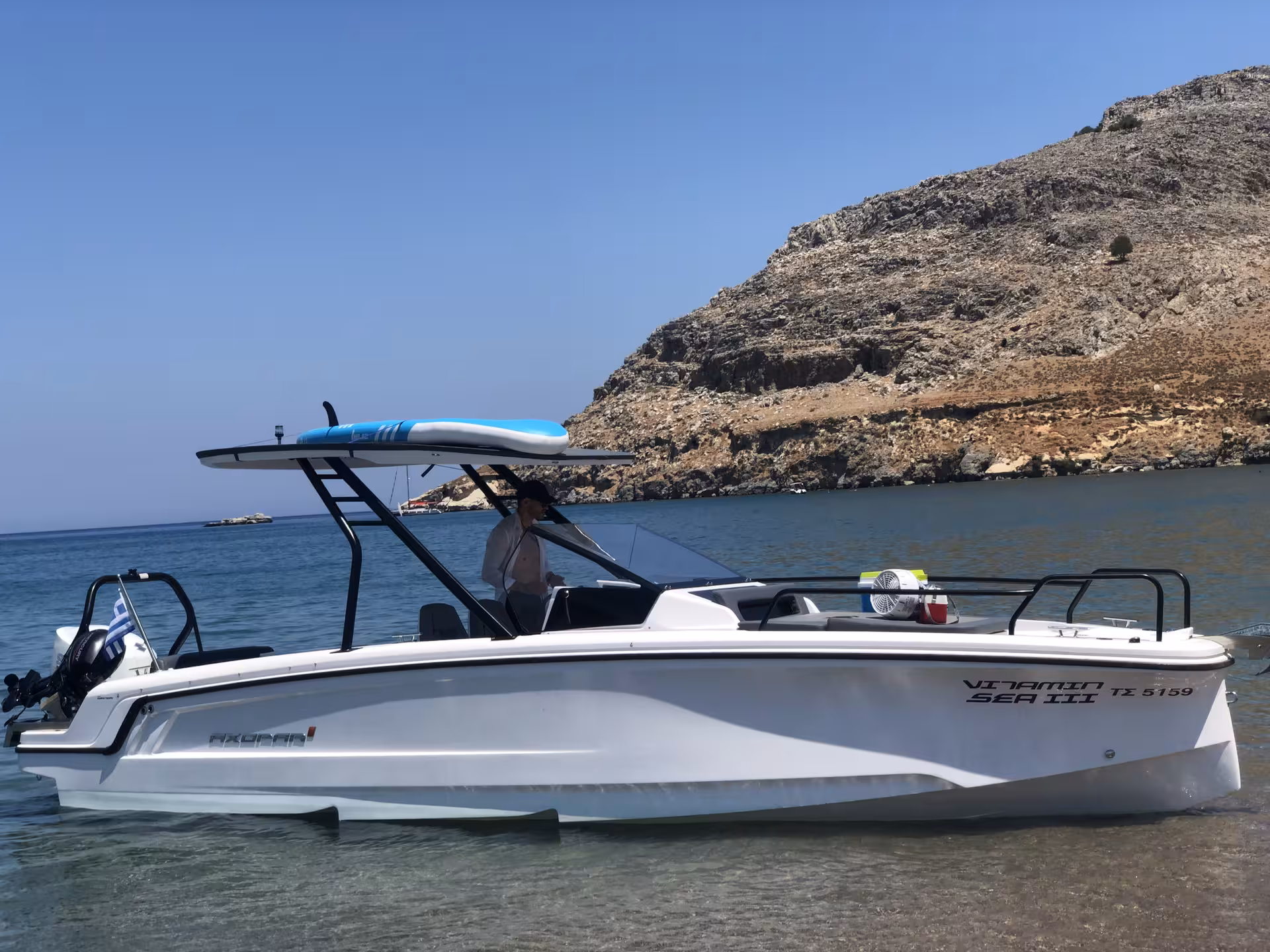 Axopar 25 CT boat rental for a half-day cruise, anchored in clear bay waters with rocky coastline backdrop