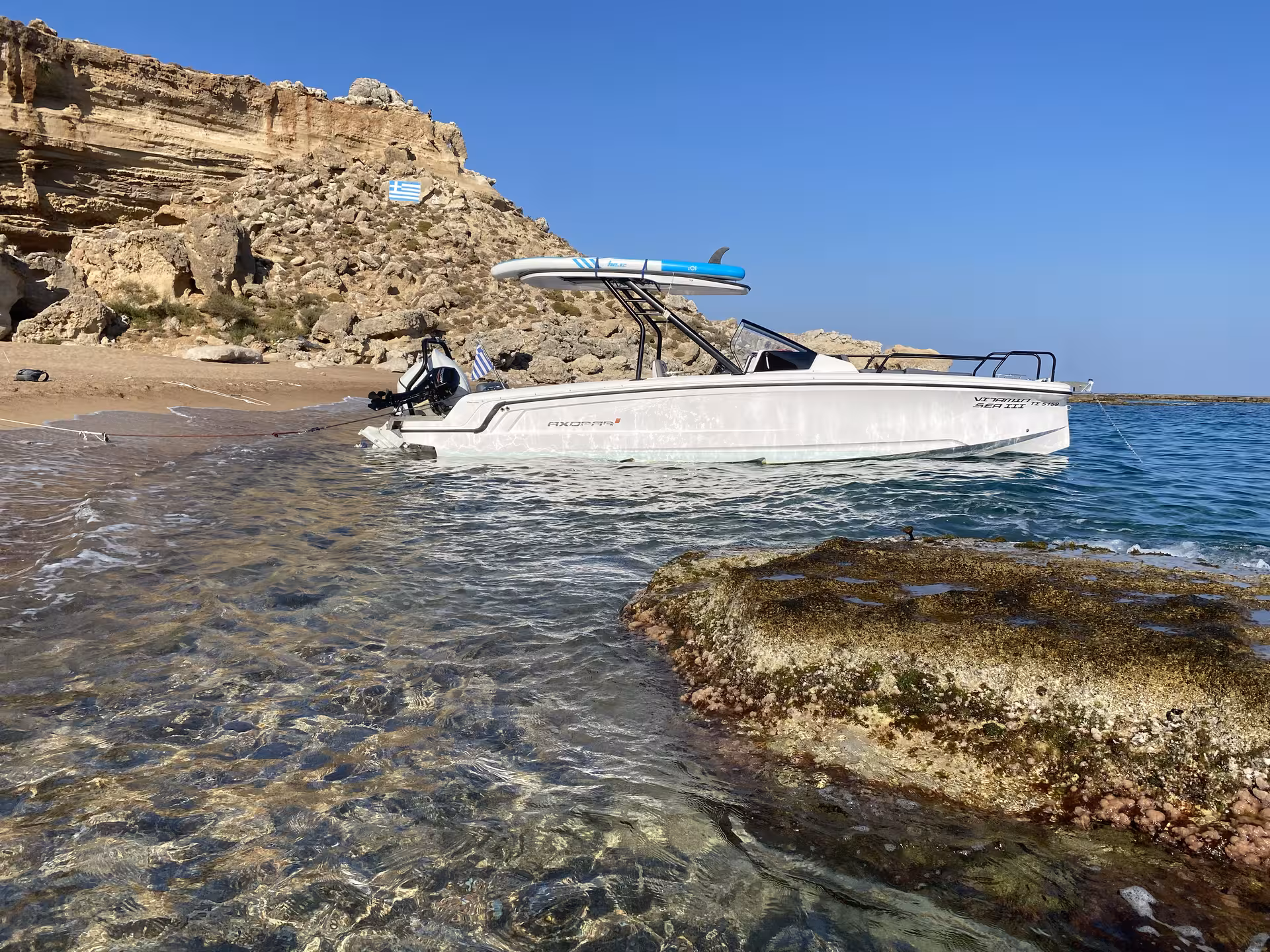 Axopar 25 CT anchored in a clear-water cove by rocky beach, ideal for half-day private boat rental