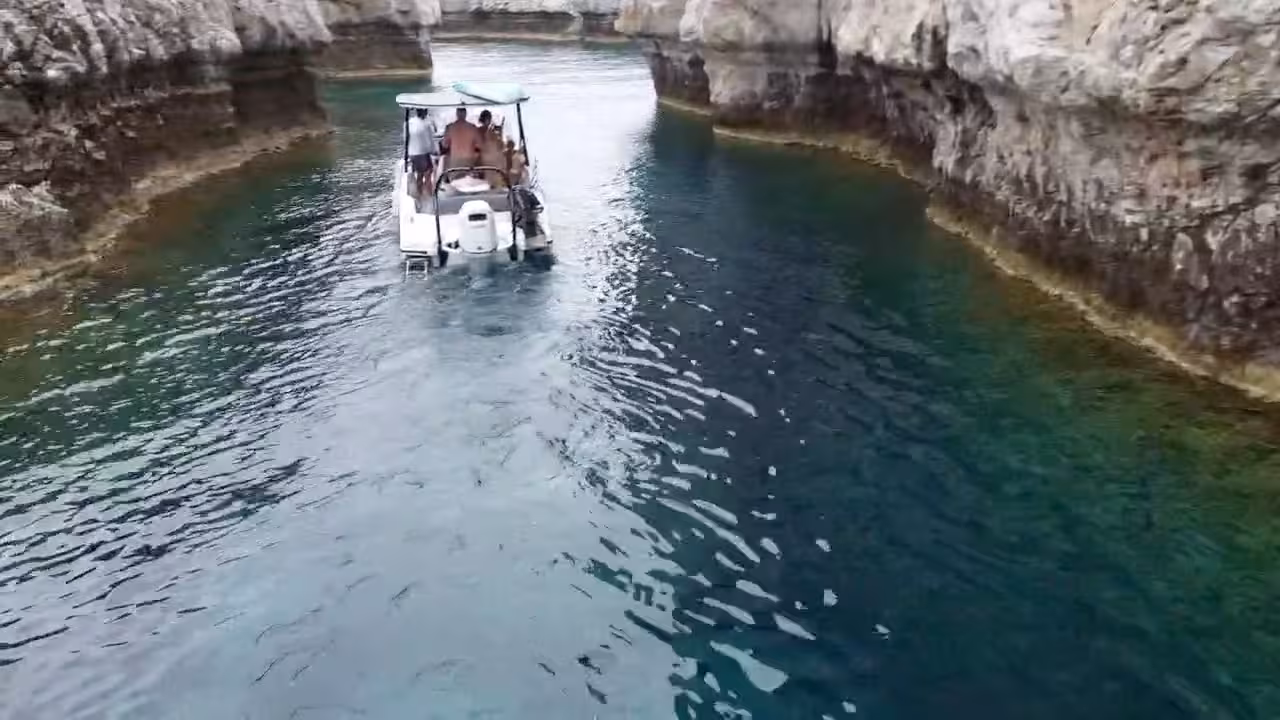 Axopar 25 CT cruising through a rocky sea canyon near Lindos, Rhodes, with crystal-clear water on a boat tour
