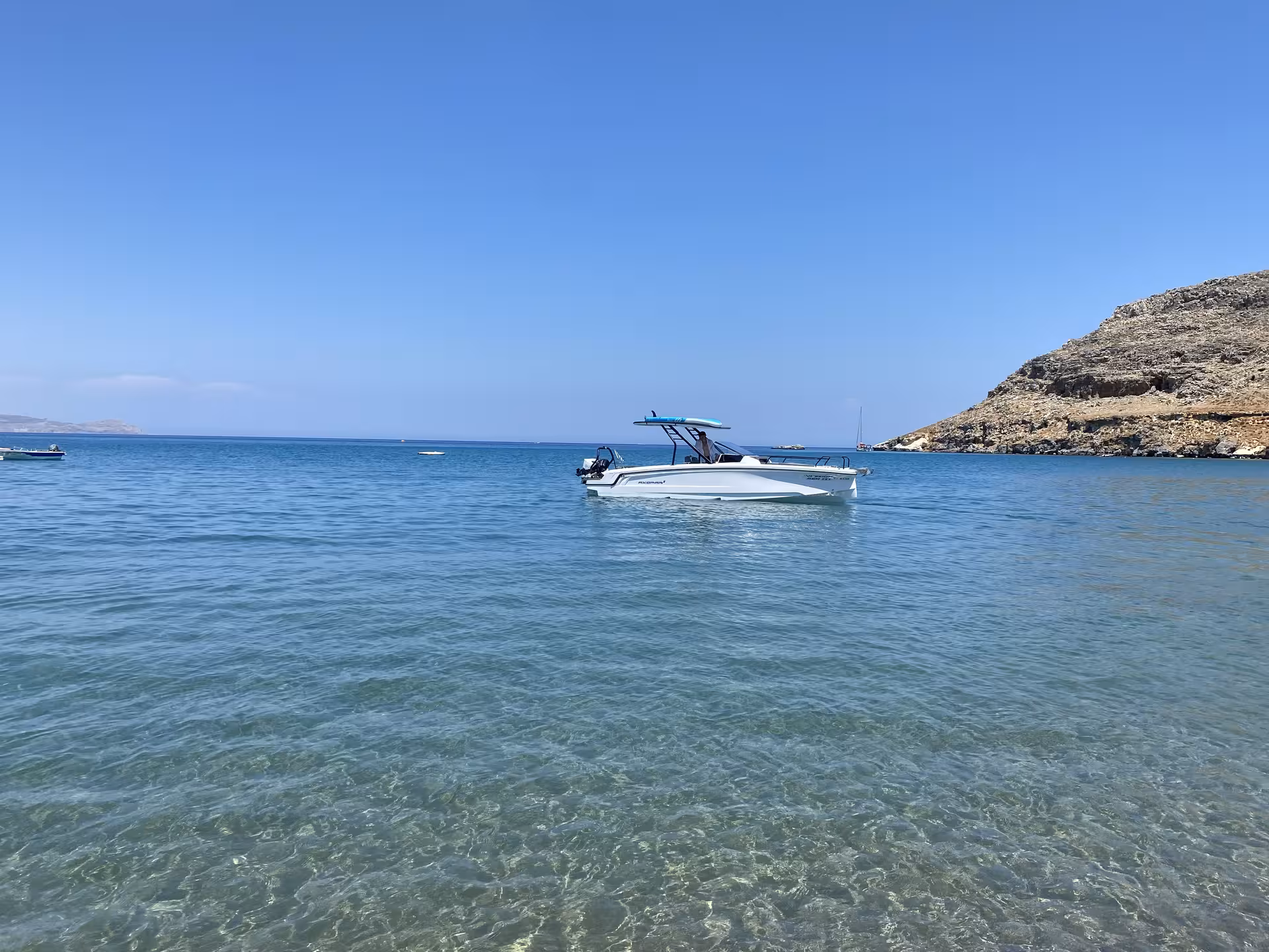 Axopar 25 CT motorboat anchored in crystal-clear Aegean bay, ideal for half-day private boat rental in Rhodes