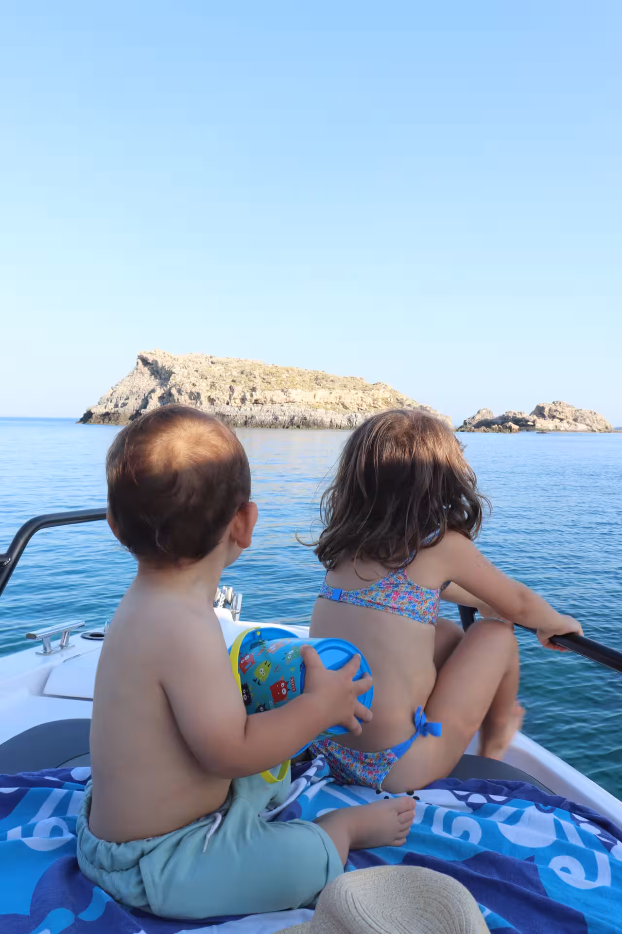 Kids relaxing on the bow of an Axopar 25 CT rental, cruising to rocky islets on a half-day boat trip