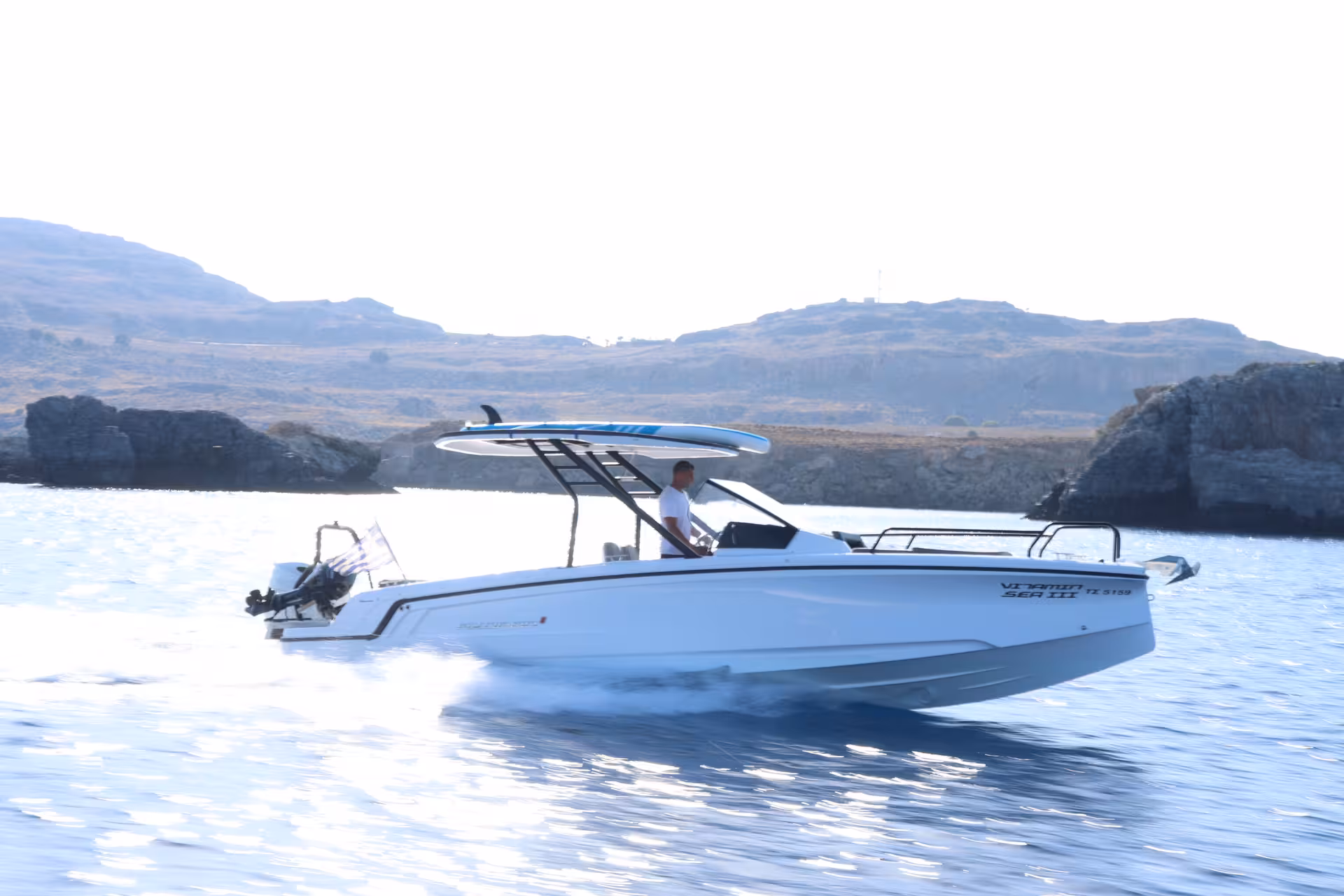 Axopar 25 CT speedboat rental for a full-day cruise, cutting through calm sea with rocky coastline backdrop