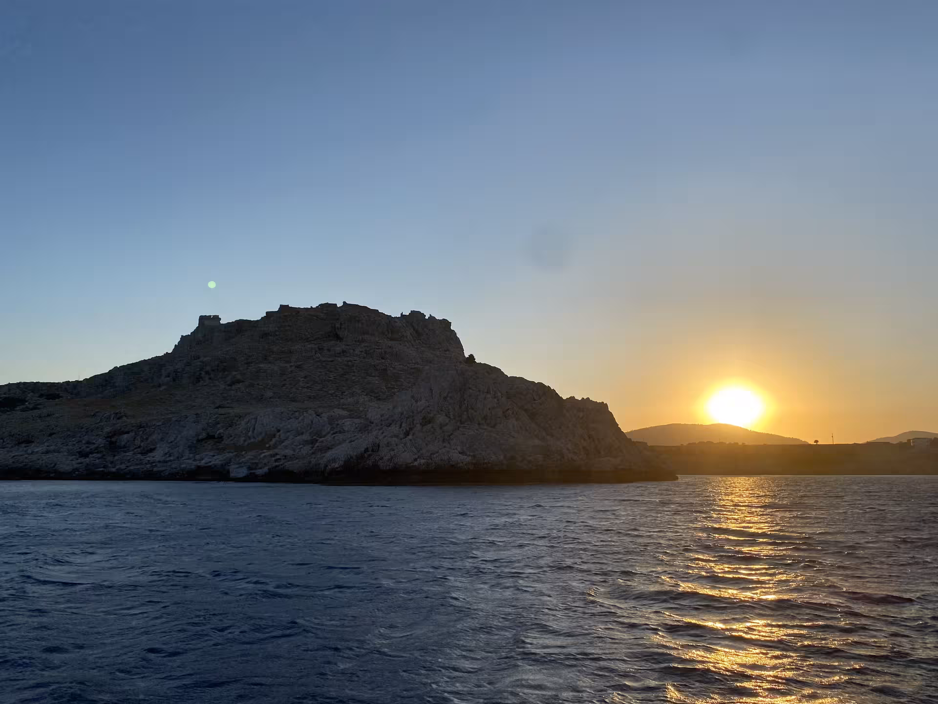 Golden sunset over rocky island coastline and shimmering sea, perfect for Axopar 25 CT sunset cruise