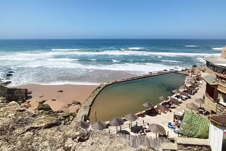 Stunning beachside pool with umbrellas at Azenhas do Mar, showcasing the coastal beauty of Sintra & Cascais.