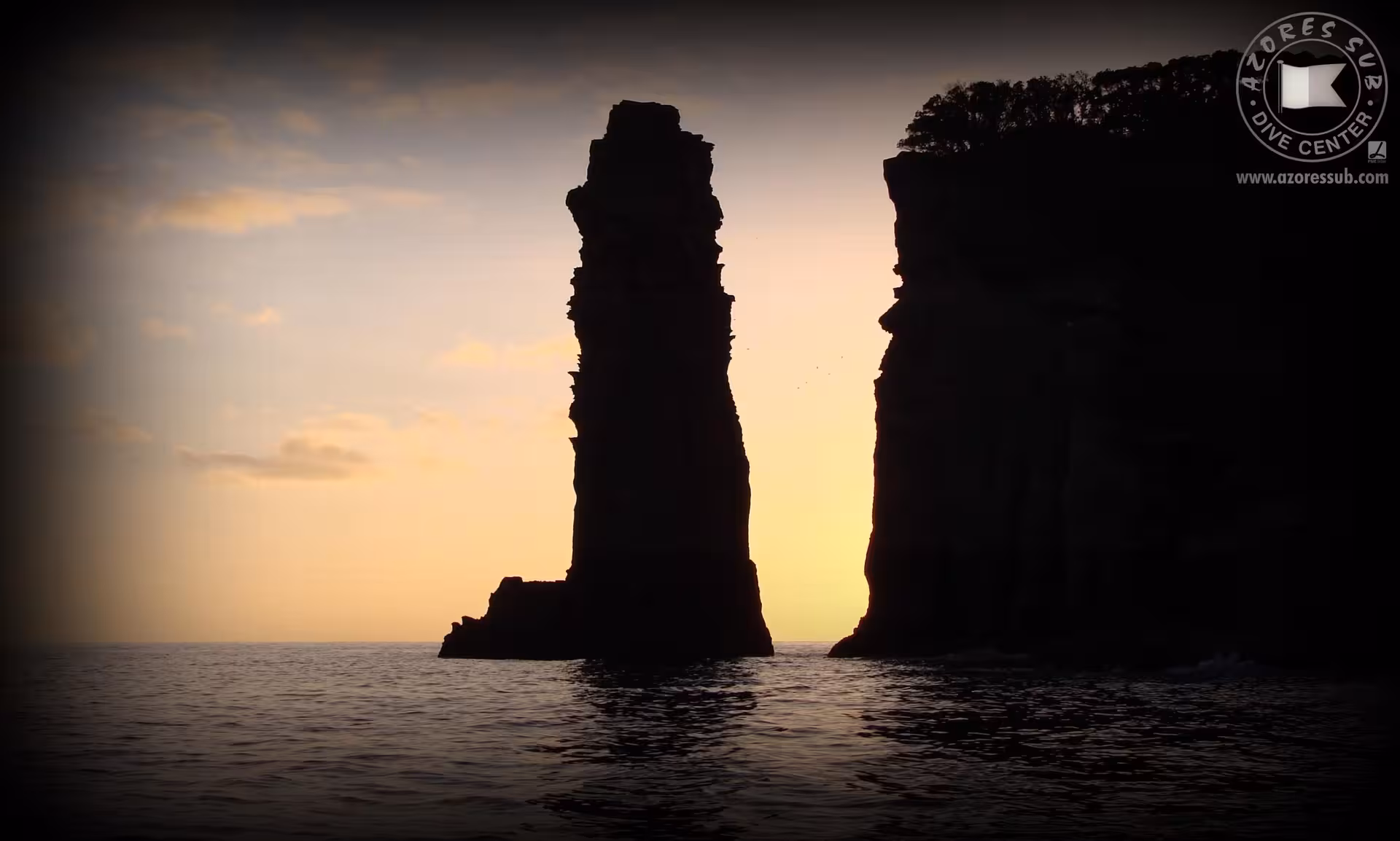 Sunset sea stack silhouette on Azores private boat tour, dramatic volcanic cliffs and calm Atlantic waters