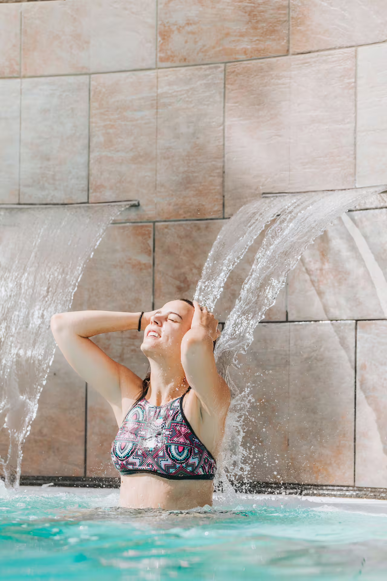 Woman enjoying hydrotherapy waterfall at Bagno di Romagna thermal spa, included in 25 min massage and pool entry