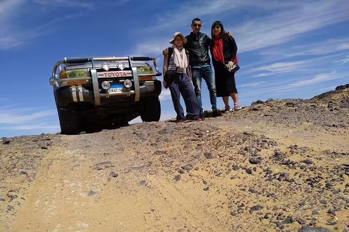 4x4 desert safari in Bahariya Oasis, Egypt, with travelers beside Toyota jeep on 3 days 2 nights tour