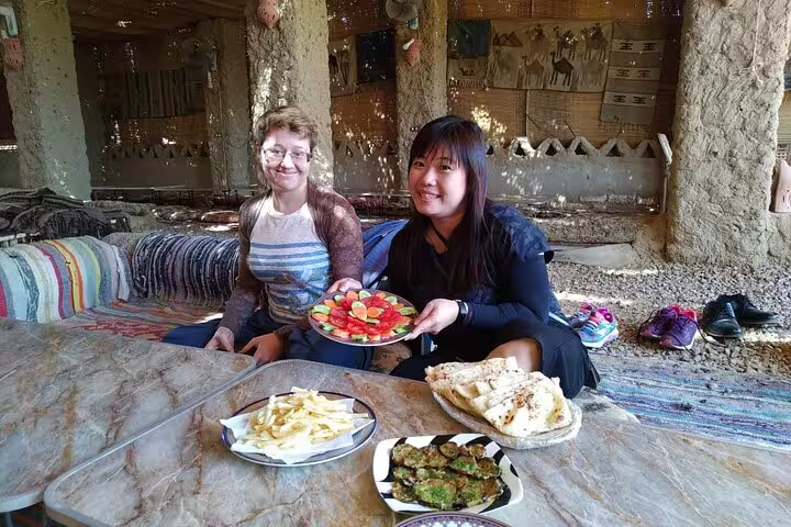 Tourists share local meal at Bahariya Oasis camp before White Desert overnight camping safari in Egypt desert